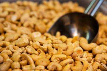 Metal scoop surrounded by raw cashew nuts. Close-up. Background for snacks and nuts