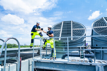 Industrial engineer teamwork working maintenance building exterior cooling systems. Male technician...