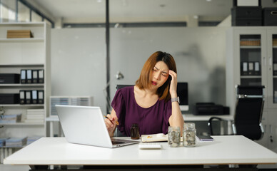 Asian woman stressed over credit card debt, holding bills in frustration.