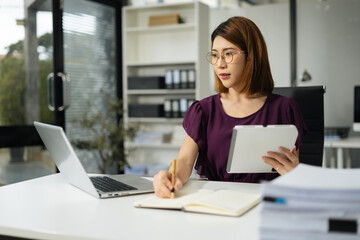 Business women hand working with tablet and laptop computer with documents on office desk in modern office.