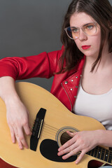 Portrait of female guitarist, she holding her musical instrument in front of her, with guitar resting on lap. She looking intently into distance, suggesting state of deep contemplation, concentration