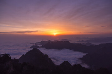 Obraz premium Sunrise paints the sky with warm colors above a wide cloud sea and mountain landscape in Wudang Mountain, China.