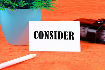 Business concept. Word writing text Consider on a white business card on an orange background
