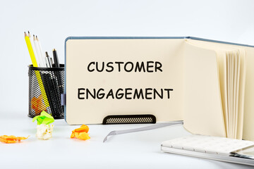CRM data management, customer loyalty concept. The concept of the info business. The text of the Customer ENGAGEMENT is written in a notebook on a blank sheet