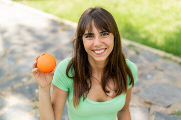 Young woman at outdoors holding an orange