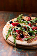 Pizza with ham, salami, tomatoes and mozzarella cheese. Rustic wooden background. Soft focus. Close up.	