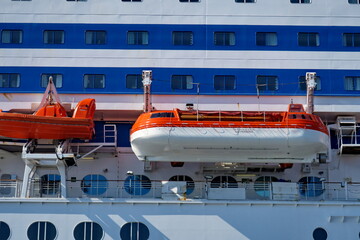 Bateau de sauvetage insubmersible orange et blanc accroché au flanc d'un bateau de passagers.