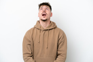 Young caucasian handsome man isolated on white background looking up and with surprised expression