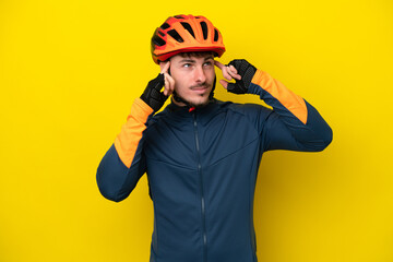 Young cyclist caucasian man isolated on yellow background having doubts and thinking