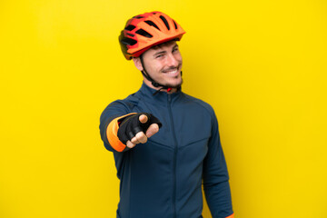 Young cyclist caucasian man isolated on yellow background pointing front with happy expression