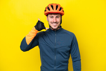 Young cyclist caucasian man isolated on yellow background making phone gesture. Call me back sign