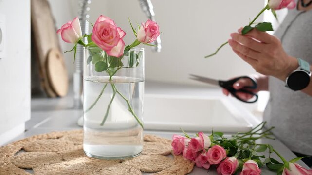 Woman Putting Roses In A Vase At Home In The Kitchen Close-Up