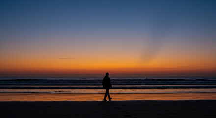 Solitary Walk on the Shoreline Under a Striking Blue and Orange Twilight Gradient