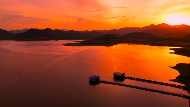 Aerial drone view of reservoir pier and mountains under colorful sunset sky