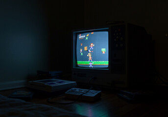 A dimly lit room featuring a vintage television playing a retro video game, with consoles nearby.