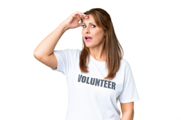 Middle age volunteer woman over isolated background doing surprise gesture while looking to the side