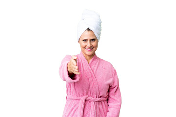 Middle age caucasian woman in a bathrobe over isolated background shaking hands for closing a good deal