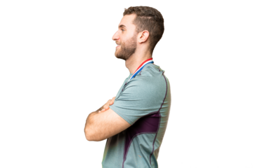 Young handsome blonde man with medals over isolated chroma key background in lateral position