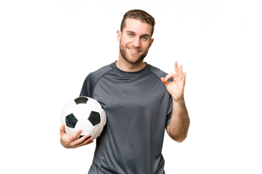 Young handsome blonde man over isolated chroma key background with soccer ball and making OK sign