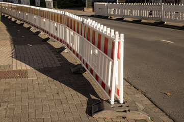 Red and white plastic road barriers separating sidewalk and street