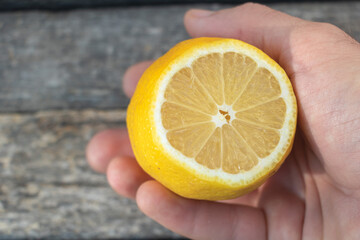 Fresh Half Lemon in Hand Closeup on Wooden Background