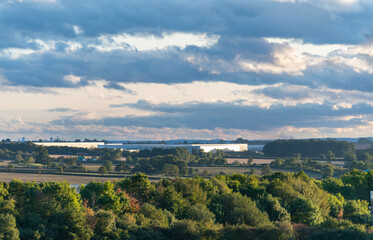 Obraz premium Large distribution warehouses in a rural setting with trees, fields, and woodlands.