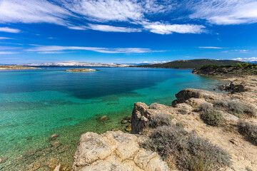 Azure water in the Adriatic Sea, rocky coast of the island of Rab, cloudy, threatening sky,
