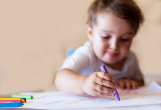 Close-up of a young Boy sitting at table learning to draw with crayons