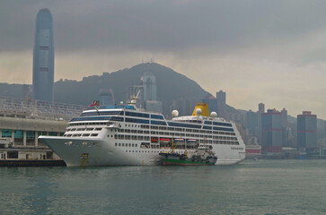 Classic cruiseship cruise ship liner Adonia at Kowloon terminal with skyline view of Hongkong Hong Kong Central business district during sunset