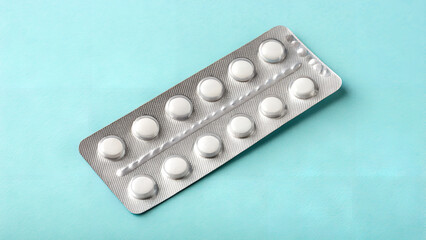 Silver blister pack of round white pills on bright blue background in clean flat lay ideal for pharmaceutical product showcases, healthcare articles and drugstore visuals