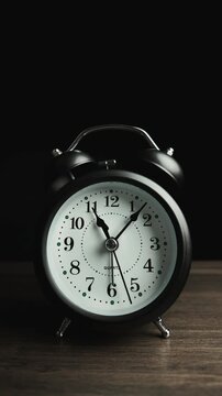 Timelapse of alarm clock on black background, vintage style. Time moves quickly, working hours, and management time concept, Footage vertical