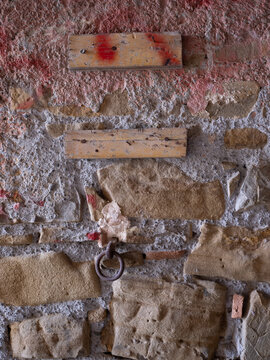 Texture di muro antico in pietra con residui di intonaco colorato e inserti in legno, sfondo materico rustico.