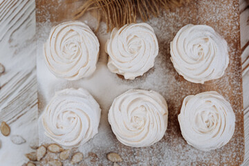 Pumpkin marshmallow meringues on a rustic wooden table, top view with powdered sugar