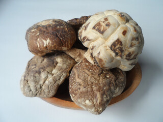 Shiitake mushrooms in a wooden plate isolated on a white background