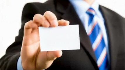 A businessman in a suit and tie holds up a blank white business card - Powered by Adobe