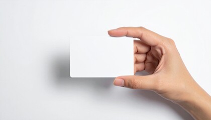 Close-up of a hand holding a blank white rectangular card. Isolated on a plain white background, this is an ideal mockup for copy space