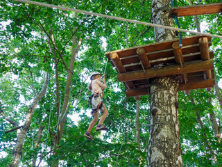 A person in a helmet and harness hanging from a rope, descending from a high wooden platform in a...