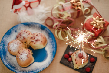 Focus on sparkle, a festive dessert featuring sugar-coated sweet rolls and berries, served with a sparkling lit candle, creates a festive atmosphere.