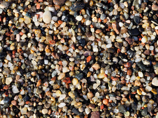 A detailed close-up shot of a textured, dry surface of colorful pebbles and sand, suitable for a natural background or wallpaper.
