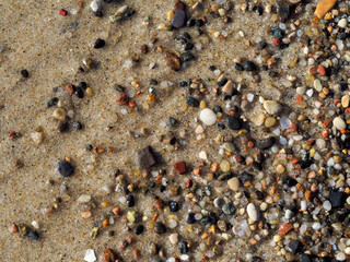 A detailed close-up shot of a textured, dry surface of colorful pebbles and sand, suitable for a natural background or wallpaper.