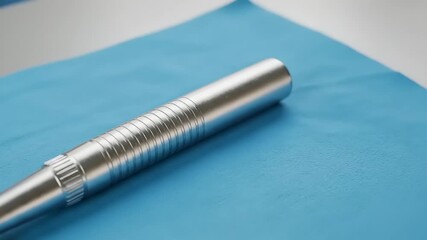 Silver dental tool on blue cloth in clinical setting