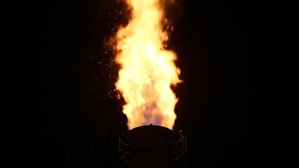 View of Natural Gas Flare Stack Burning at Night, Releasing Heat and Sparks Into the Dark Sky Over Industrial Site
