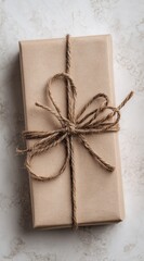 Wrapped gift box wrapped in brown paper tied with twine, centered on a textured marble-like surface
