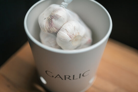 Close up of garlic bulbs in mesh bag inside canister