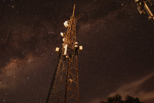 Telecommunications towers illuminated at night with Milky Way