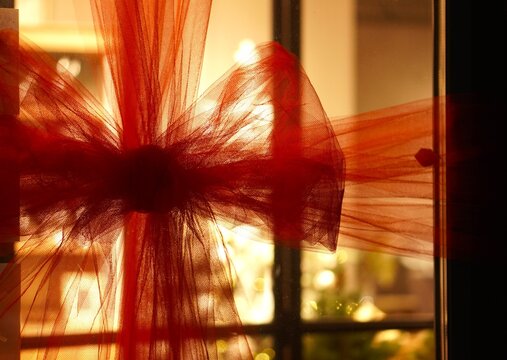 Red organza bow elegantly tied on glass door with Christmas setting in the house
