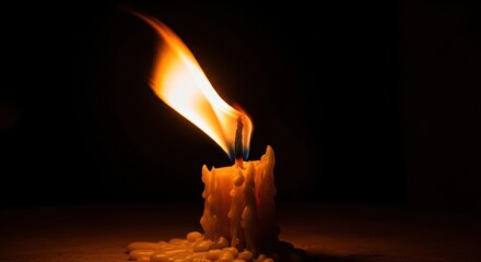 Melted candle with bright flame in dark ambience