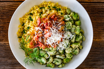 Boiled broad beans with bulgur, fried bacon and onion on wooden table	