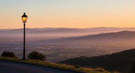 Sunset over rolling hills and cityscape with illuminated streetlamp