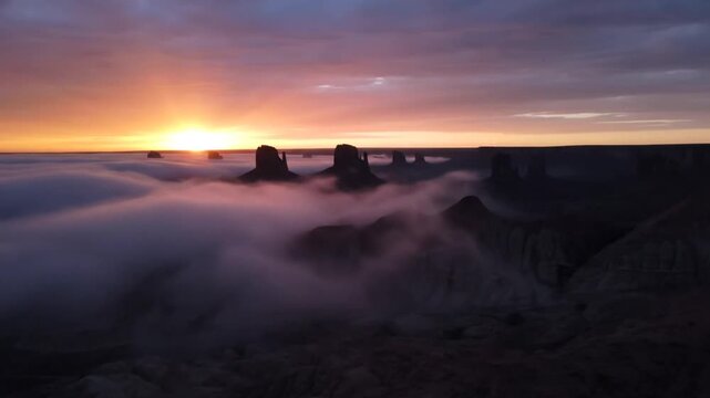 Sunrise over monument valley, usa, with dramatic rock formations emerging from a thick blanket of lowlying fog and mist